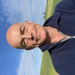bald man wearing a blue jumper with a blue sky background