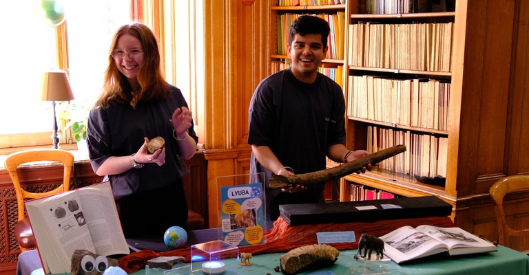 A woman and man smiling behind a table covered in rocks and minerals