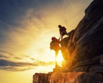 People helping eachother climb up mountain