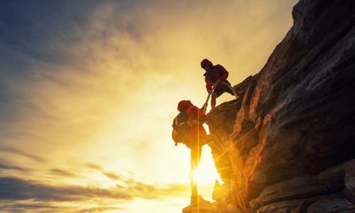 People helping eachother climb up mountain