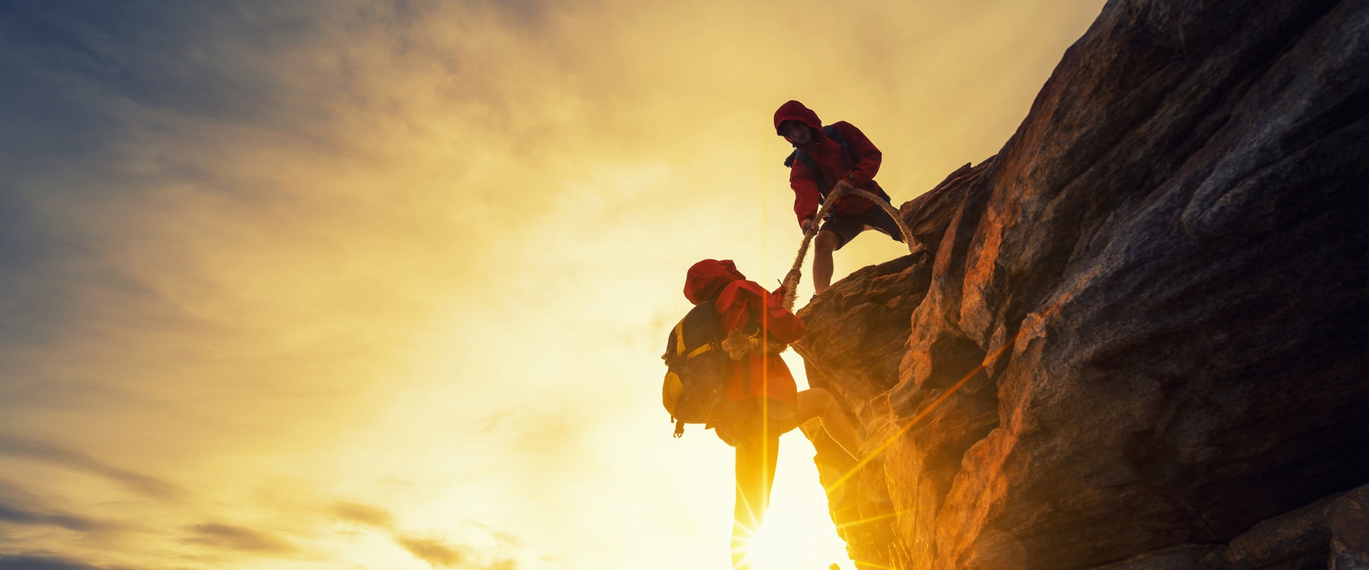 People helping eachother climb up mountain
