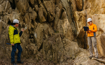 two people in high vis jackets and hard hats inspecting a rocky area