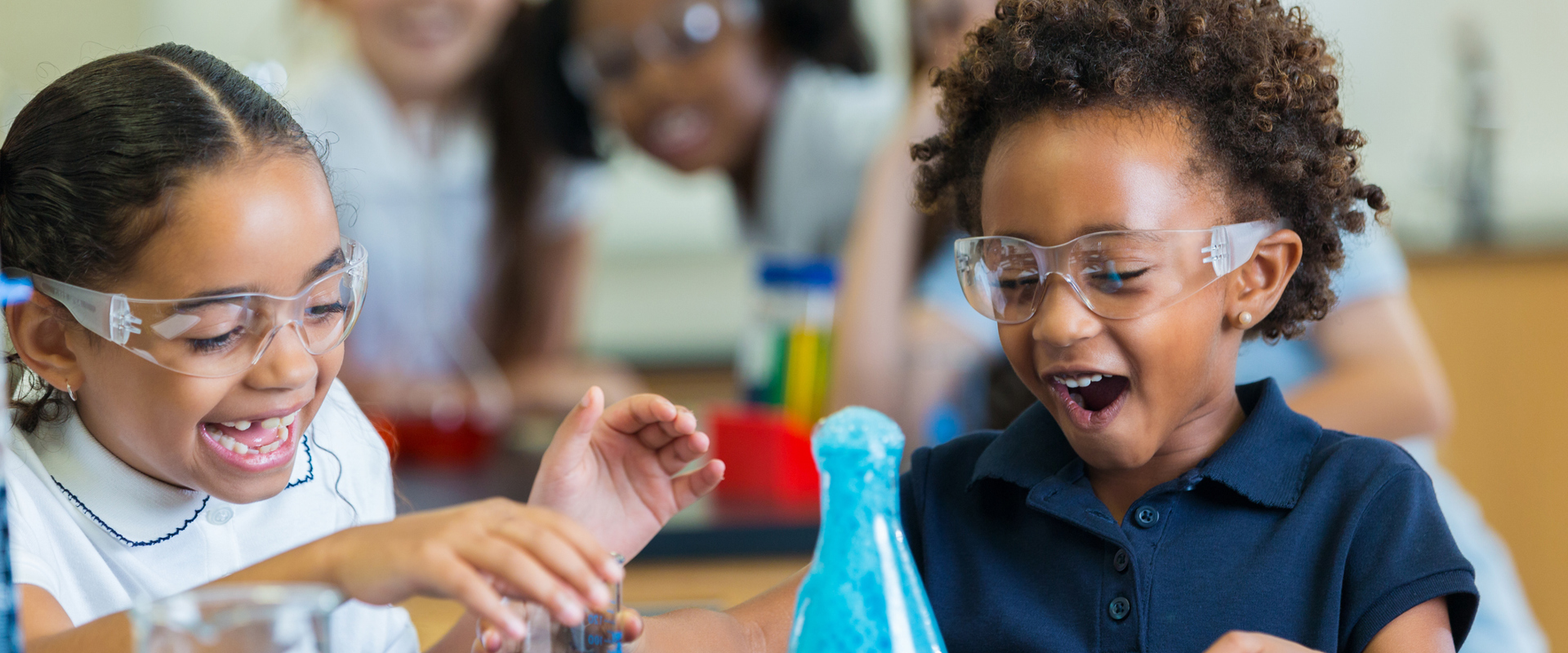 two small black girls smiling excitedly at their bubbling vial science experiment