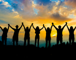 Silhouettes of a group of people holding hands with their arms in the air