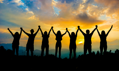 Silhouettes of a group of people holding hands with their arms in the air