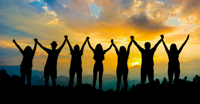 Silhouettes of a group of people holding hands with their arms in the air