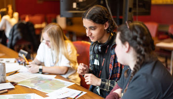 Asian boy and two girls looking at maps on a table
