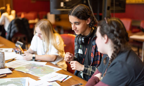 Asian boy and two girls looking at maps on a table