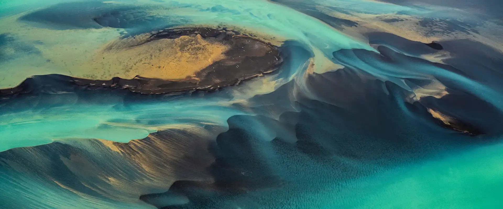 A unique green-coloured solar flare flowing through sandy dunes.