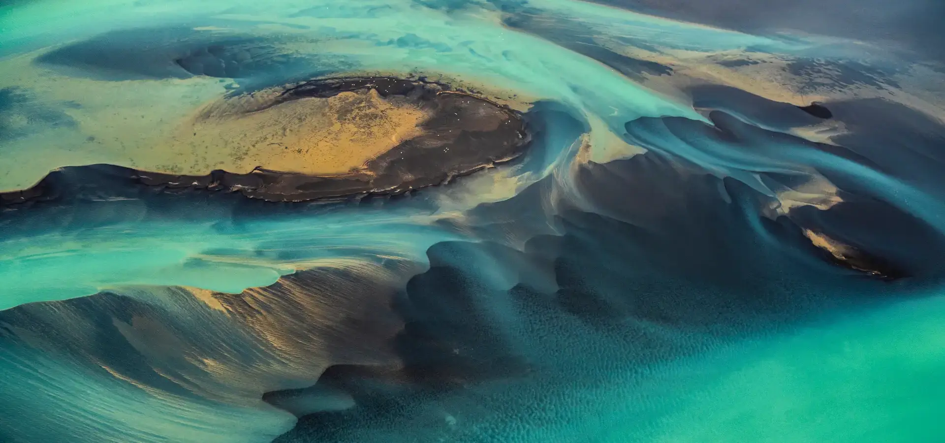 A unique green-coloured solar flare flowing through sandy dunes.