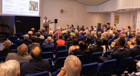 People seated in a lecture theatre listening to a woman speaking