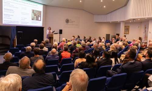 People seated in a lecture theatre listening to a woman speaking