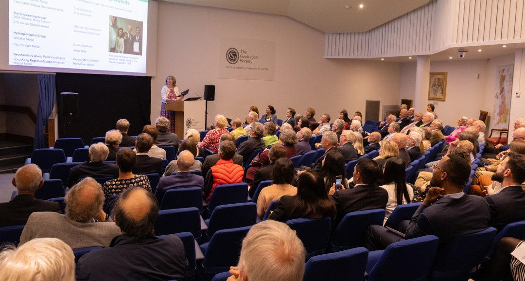 People seated in a lecture theatre listening to a woman speaking