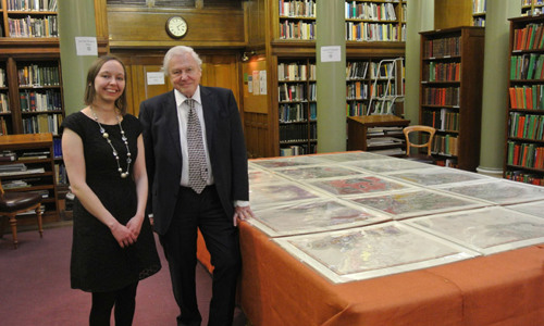 Victoria Woodcock and Sir David Attenborough standing in front of William Smith's map in the Geological Society's Upper Library