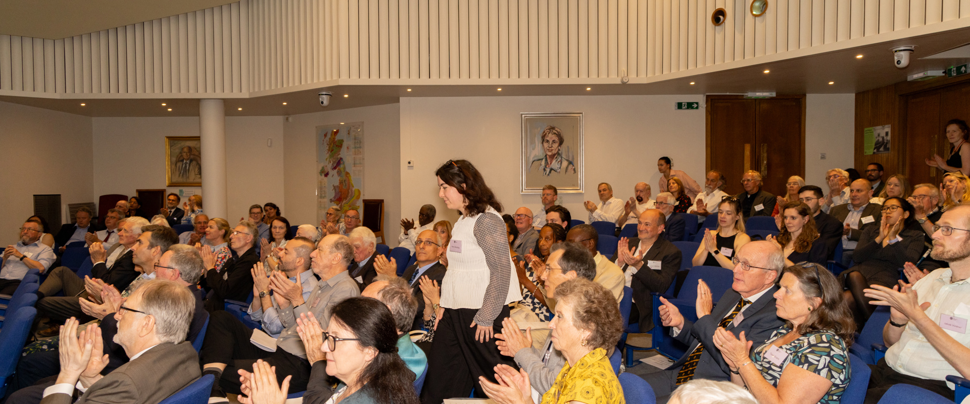 Dr Nemi Walding award winner walks down the lecture theatre aisle towards the stage