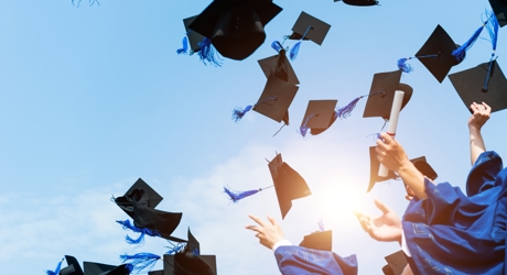 Graduates throwing graduation caps in the air
