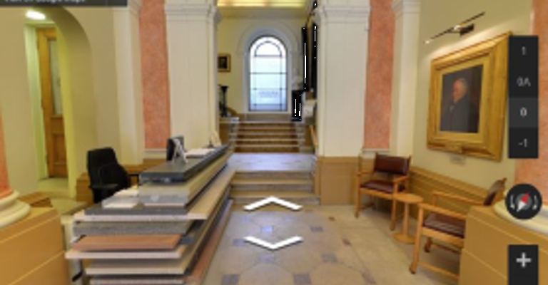 Interior view of The Geological Society's reception area, featuring a desk, staircase, and framed artwork on the wall.