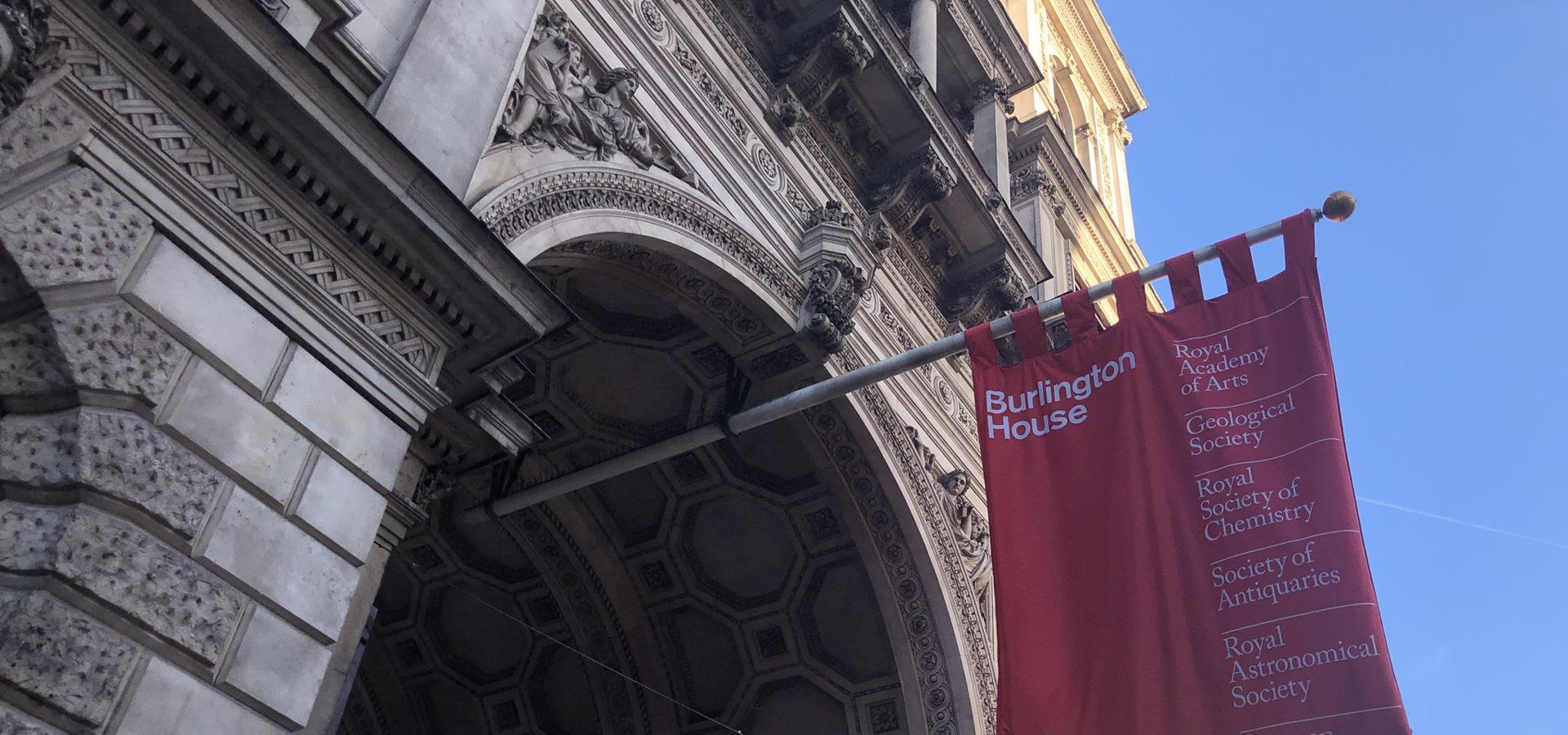 arched entrance to period building with red flag hanging over it