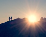 People holding hands on hill in sunset