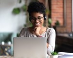 Woman at laptop with headset on smiling