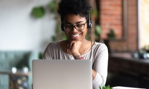 Woman at laptop with headset on smiling