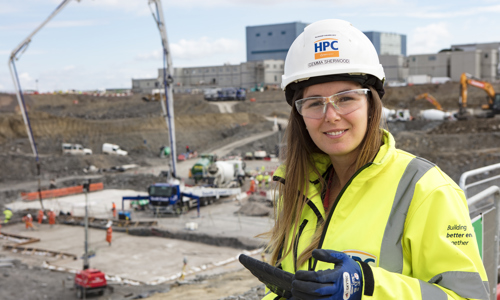 White woman in hard hat and high vis jacket standing in a work site