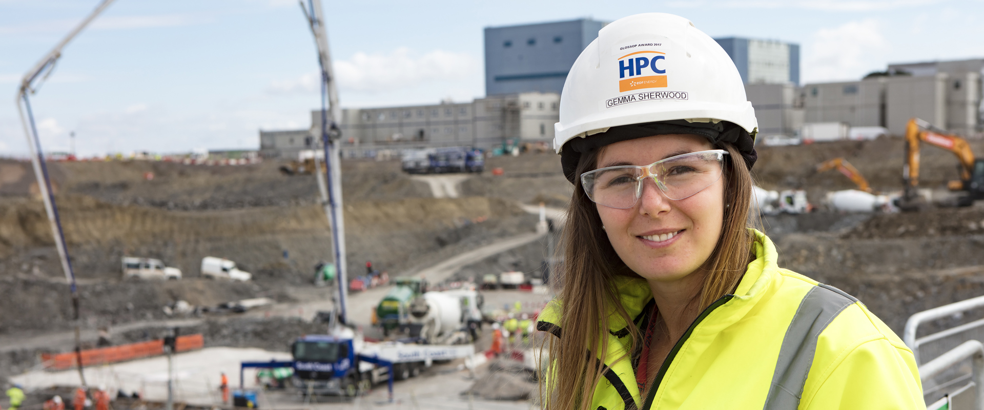 White woman in hard hat and high vis jacket standing in a work site