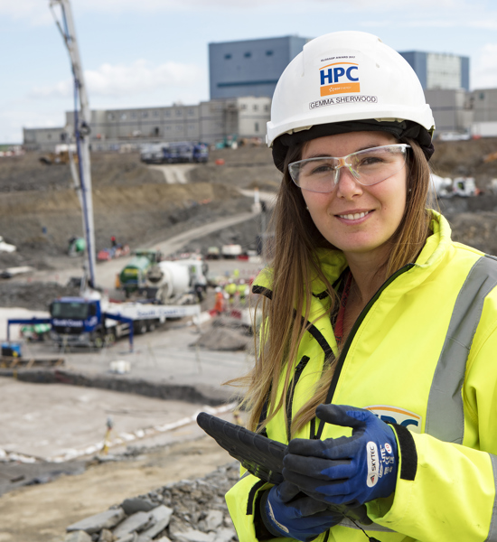 White woman in hard hat and high vis jacket standing in a work site