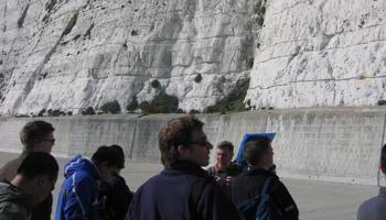 A group of people standing in front of a chalky cliff face with blue sky in the background