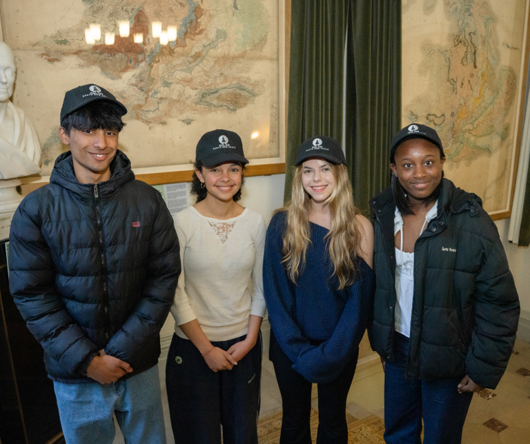 Two young black girls and one young white girl and one young Asian boy smiling at the camera
