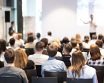 Group of people sat in lecture hall watching a man giving a presentation