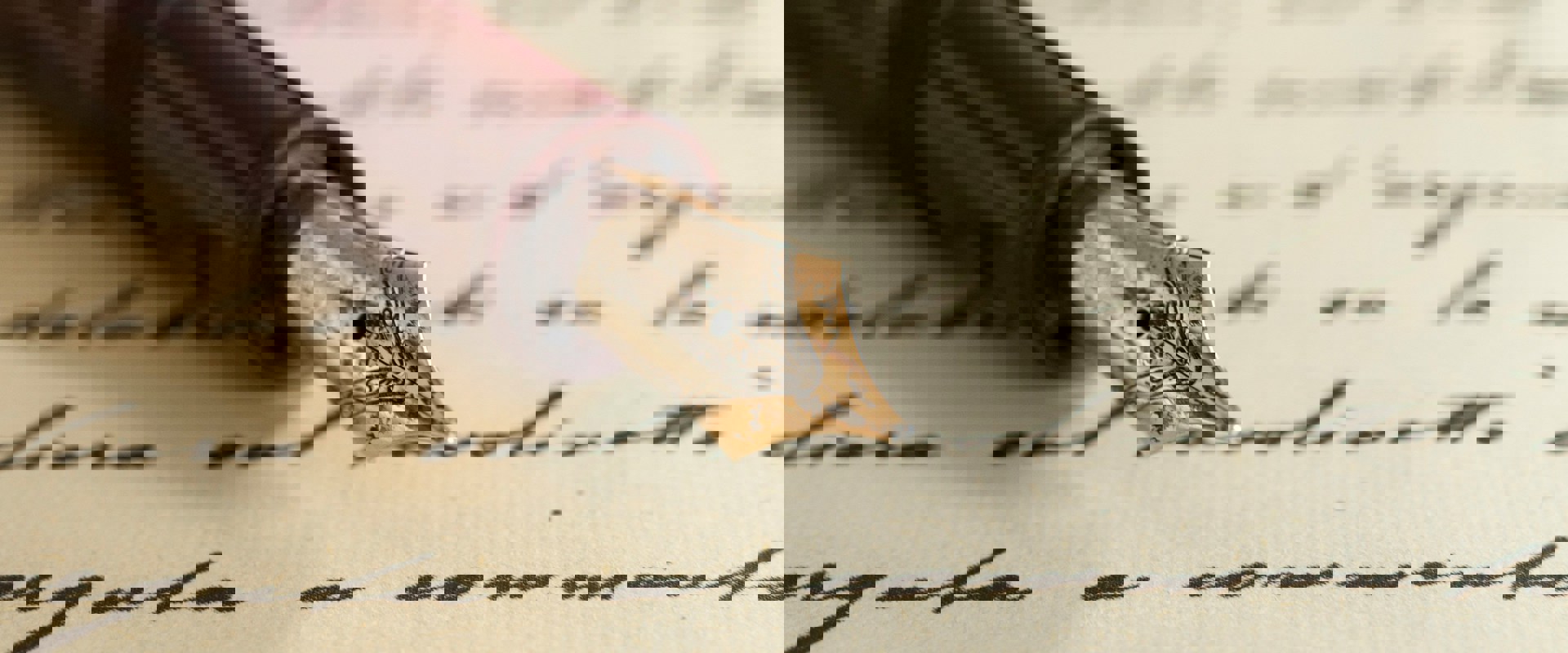 A sheet of paper with black handwriting on which rests the nib and first half of a brown fountain pen