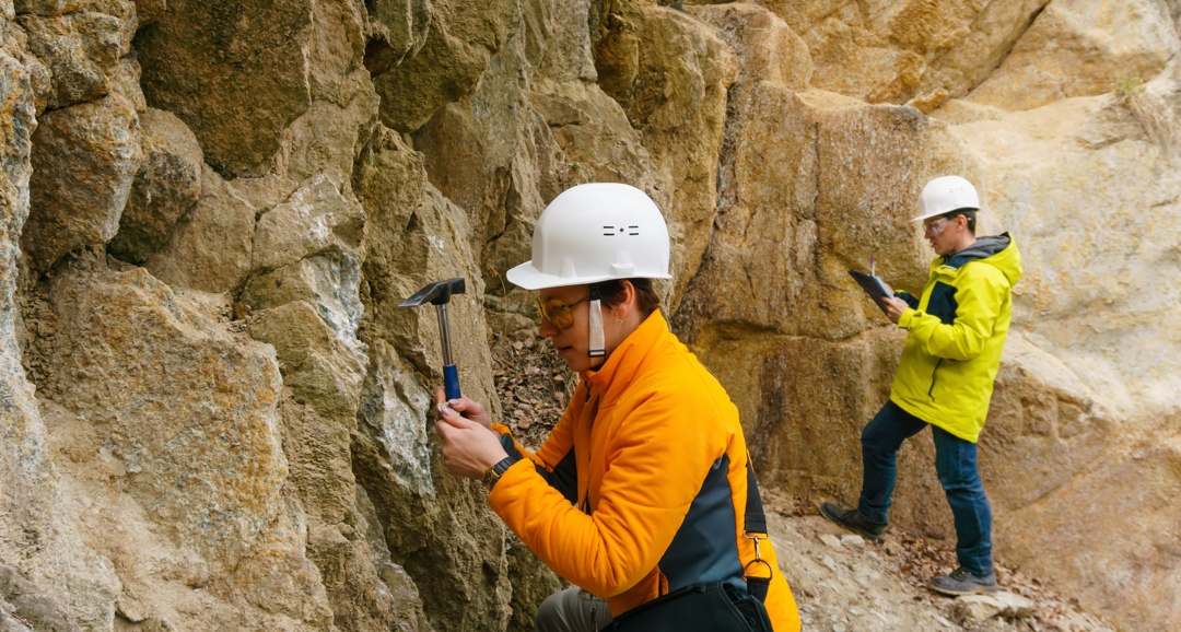 People in hardhats with hammers assessing stones