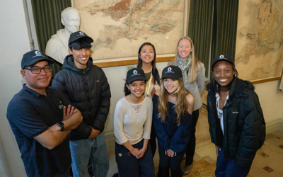 four young people stood with 3 adults smiling at the camera