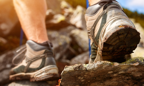 Person in walking boots stepping over rocks