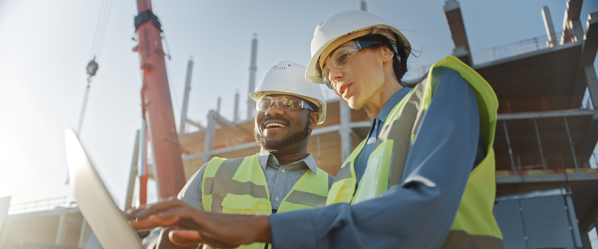 2 people in hardhats on site looking at laptop