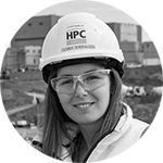 Woman smiling wearing a hard hat and safety glasses