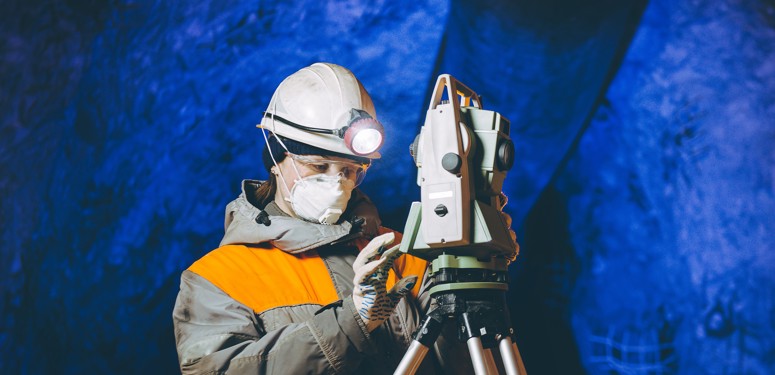 Woman in hardhat in mine assessing engineering equipment