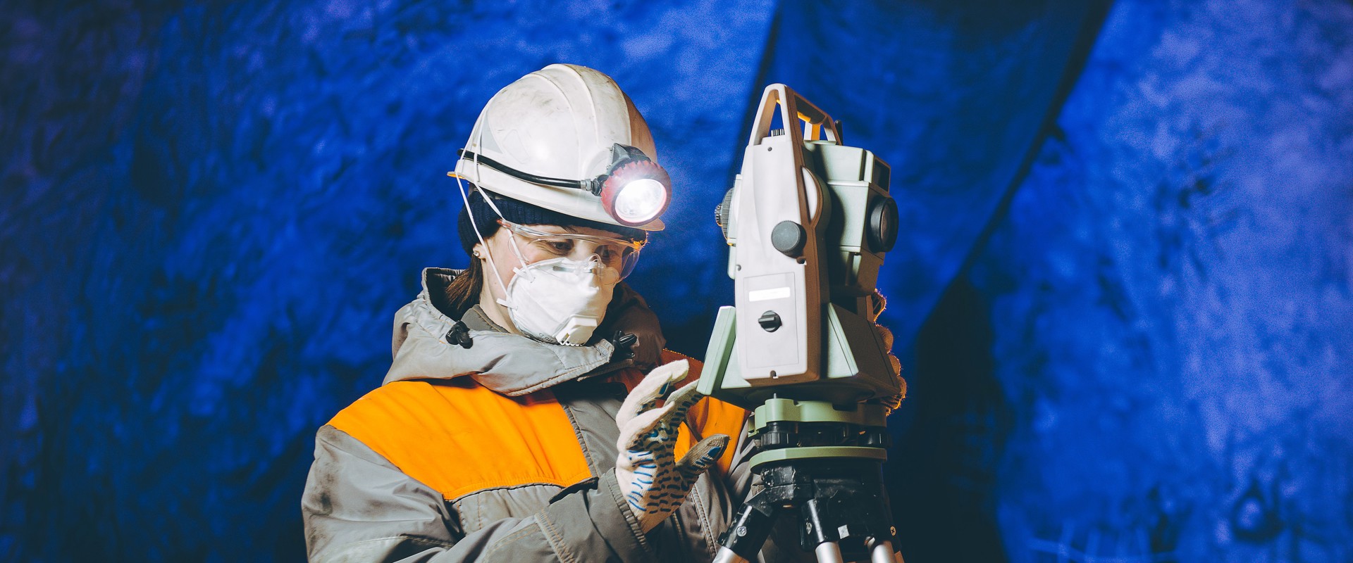 Woman in hardhat in mine assessing engineering equipment