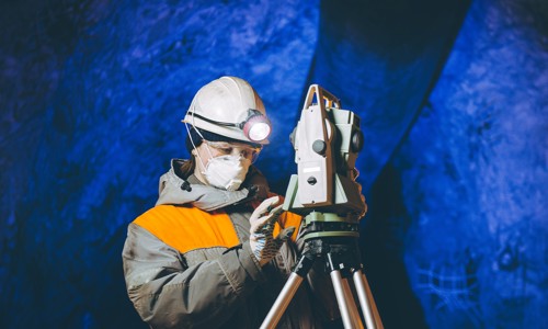 Woman in hardhat in mine assessing engineering equipment