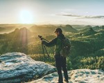 Man on mountaintop holding a camera tripod