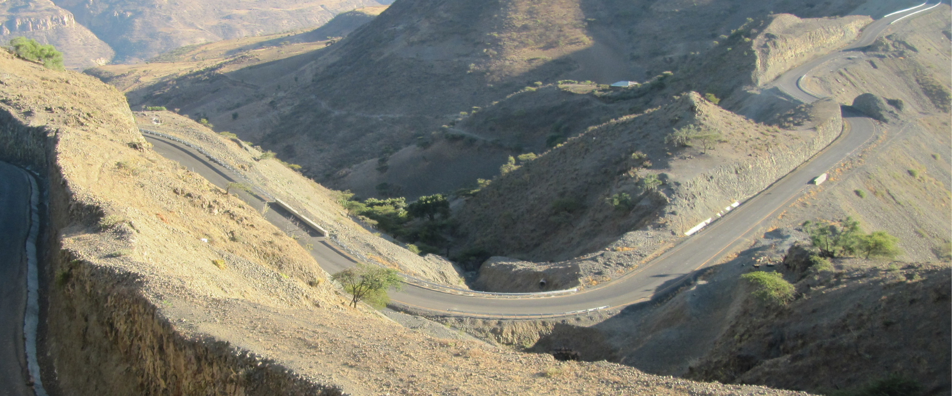 Rock face with road cutting into the hills. Cars driving on the road