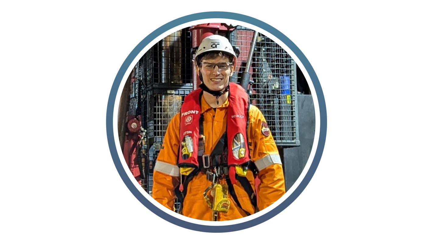 young white man with high vis orange coat and white hard hat and life jacket around his neck