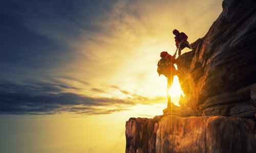 Image first climber helping second climber over a rocky ledge Shutterstock 760304731