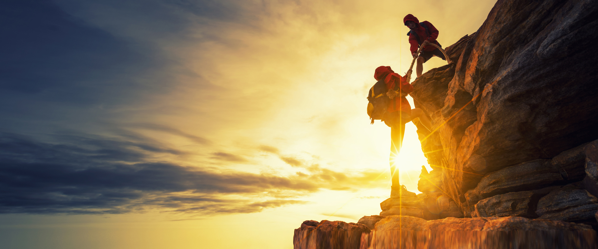 Image first climber helping second climber over a rocky ledge Shutterstock 760304731